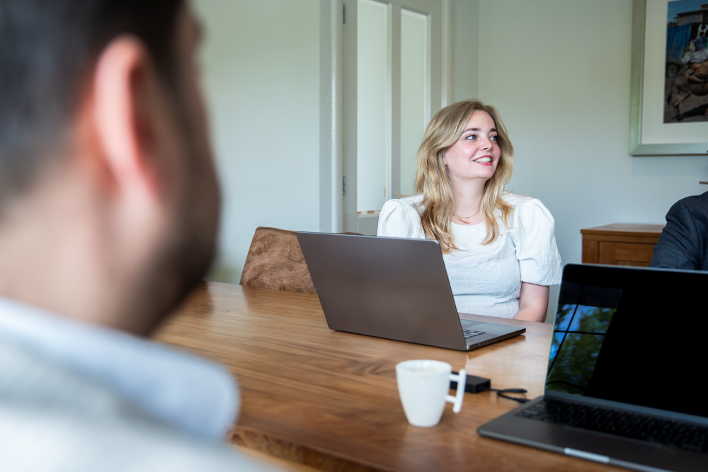 Raezel van Duuren zit met een glimlach in een overleg. Foto ter illustratie bij de vacature projectmanager Bouw & Vastgoed